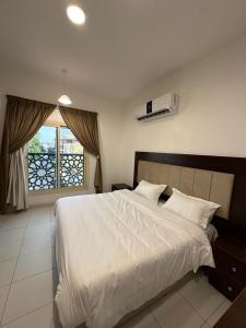 a bedroom with a white bed and a window at دبليو تاون للشقق المخدومة - W Town Serviced Apartments in Jeddah