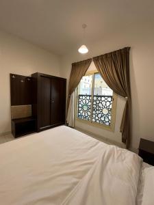 a bedroom with a large white bed and a window at دبليو تاون للشقق المخدومة - W Town Serviced Apartments in Jeddah