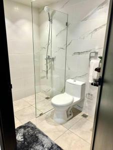a bathroom with a toilet and a glass shower at Wendy Luxury Tower in Santiago de los Caballeros