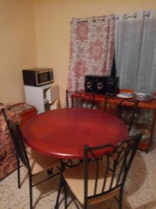 a red dining room table with chairs and a microwave at Boothe's Palace in Oracabessa