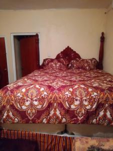 a bedroom with a bed with a red and gold bedspread at Boothe's Palace in Oracabessa