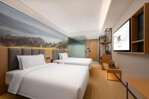 um quarto de hotel com duas camas e uma televisão em True Go Hotel - Shenzhen Futian Huaqiang North em Shenzhen