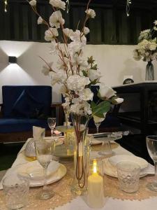 una mesa con un jarrón con flores blancas. en شالية خاص مع جناح فندقي en Ḩayy aş Şāliḩīyah