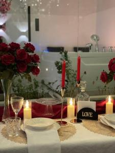 una mesa con rosas rojas y velas en شالية خاص مع جناح فندقي en Ḩayy aş Şāliḩīyah