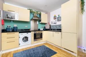 cocina con armarios blancos, lavadora y secadora en Dennison House, en Londres
