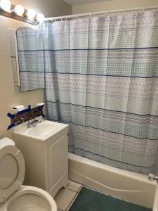 a bathroom with a toilet and a shower curtain at Private Queen Bedroom B house shared common spaces in Fort Pierce