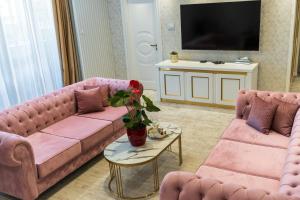 a living room with two pink couches and a tv at Queen Palace in Novi Sad