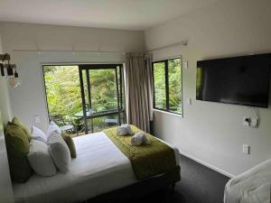 a bedroom with a large bed with a flat screen tv at Forest View Franz Josef in Franz Josef