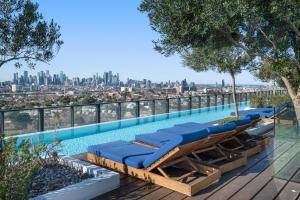 a pool with lounge chairs and a view of the city at FLEMINGTON - Melbourne City Views in Melbourne
