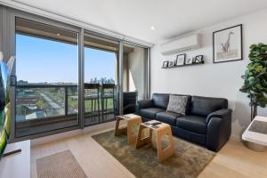 a living room with a couch and a large window at FLEMINGTON - Melbourne City Views in Melbourne