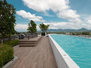 a swimming pool with benches and the water at Excellent 2bd apartment with a patio in Phuket