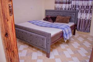 a bedroom with a bed with a wooden headboard at Dandy Home, 2 BdRm, Estn Bypass Kamakis Greenspot in Ruiru