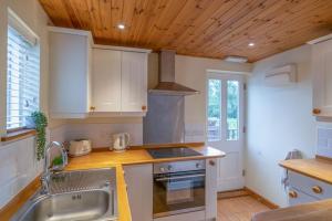 cocina con armarios blancos y techo de madera en The Railway Weigh Office (Cliburn) en Penrith