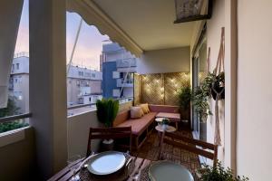 einen Balkon mit einem Sofa und einem Tisch in der Unterkunft Athens Premium Suites - Sunny 2 Bedroom Suite with Parking in Athen