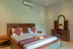 a bedroom with a large bed and a mirror at Warsa's Garden Bungalow and Spa in Ubud