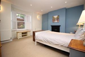 1 dormitorio con paredes azules, 1 cama y escritorio en orwell villa elegant period 5 bed close to town sleeps 15, en Cheltenham