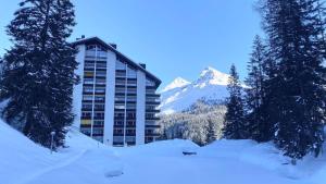 a building in the snow with a mountain in the background at Rothornblick 6 in Arosa