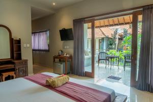 a bedroom with a bed and a sliding glass door to a patio at Warsa's Garden Bungalow and Spa in Ubud