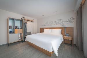 um quarto com uma grande cama branca e um espelho em UrCove by HYATT Nanjing Downtown em Nanquim