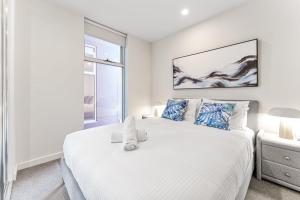 ein Schlafzimmer mit einem großen weißen Bett und einem Fenster in der Unterkunft Central Cty Racecourse Road LivingSpace in Melbourne