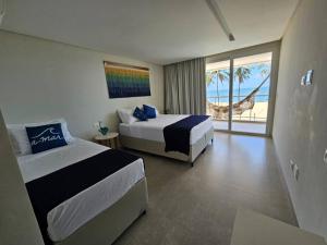 Barra do SirinhaémにあるBeira mar com vista espetacular! Quinta da Barra!のベッドルーム1室(ベッド2台付)が備わり、海の景色を望めます。