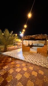 a pavilion with a table and benches at night at Thenoblejewel in Al Laqīţah