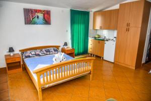 a bedroom with a bed and a kitchen with green curtains at Studios Kalina in Budva