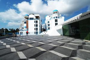 two white buildings with a checkered floor in front at Costa Village Jacuzzi Bangsaray in Bang Sare