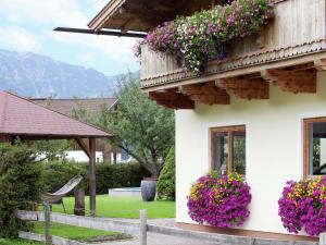 a white house with flowers on the side of it at Alluring Apartment with Swimming Pool in Waidring Tyrol in Waidring