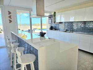 a kitchen with a bar with stools and a view of the ocean at Beira mar com vista espetacular! Quinta da Barra! in Barra do Sirinhaém