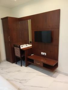 Zimmer mit einem Schreibtisch, einem TV und einem Tisch in der Unterkunft The Amur Falcon Inn & Resorts in Rāja Sānsi