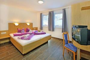 een slaapkamer met een bed met paarse kussens en een tv bij Terraced Houses Oliver L ngenfeld in Längenfeld