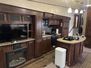 a kitchen with wooden cabinets and a flat screen tv at Entire 1bedroom RV Camper in Fort Pierce