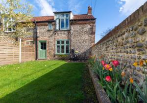 a brick house with a retaining wall and flowers at Warborough House East in Kelling