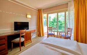 コステルマーノにあるBoffenigo Panorama & Experience Hotelのベッド、テレビ、バルコニーが備わるホテルルームです。
