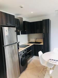 La cuisine est équipée de placards noirs et d'un réfrigérateur en acier inoxydable. dans l'établissement Luxurious 2 Bedroom Apartment @Embassy Garden, à Accra