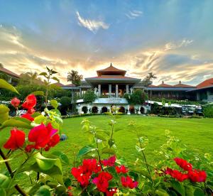 een groot gebouw met rode bloemen ervoor bij Bali Dynasty Resort in Kuta