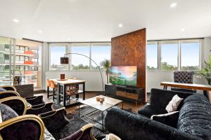 a living room with couches and a flat screen tv at Elegant 1-Bed by Riverside Park & Amenities in Sydney