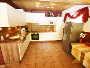 eine Küche mit weißen Schränken und einem Kühlschrank aus Edelstahl in der Unterkunft Spacious Chalet in Piesendorf with Sauna in Piesendorf