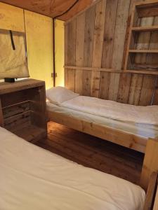 エーペにあるLuxe Safaritent voor het hele gezin I 6 personenの木製の壁の部屋にベッドが2つある