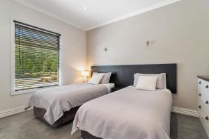 two beds in a bedroom with a window at Valley Villa - Cardrona Holiday Home in Cardrona
