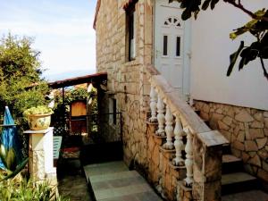 ein Steinhaus mit einer weißen Tür und einer Treppe in der Unterkunft Apartment Ma're in Supetar