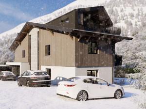 dos autos estacionados frente a una casa en la nieve en Bergzeit Apartments right on the ski slope, en Saalbach Hinterglemm