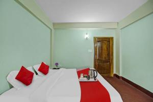 - une chambre avec un lit blanc et des oreillers rouges dans l'établissement Flagship Evergreen Guest House, à Shillong