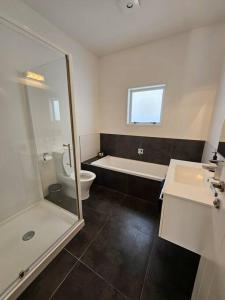 ein Badezimmer mit einer Badewanne, einem WC und einem Waschbecken in der Unterkunft Golden Sands Beachside Cottage in Papamoa