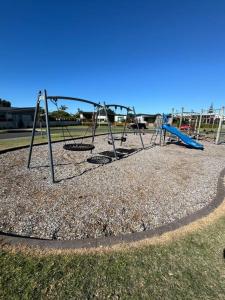 a playground with a swing set in a park at Golden Sands Beachside Cottage in Papamoa