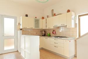 瓦爾迪安諾蒙托波利的住宿－Tana Rosa，厨房配有白色橱柜和白色冰箱。