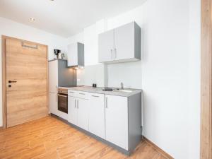 a kitchen with white cabinets and a wooden door at Beautiful and Cosy Flat in Wagrain in Wagrain