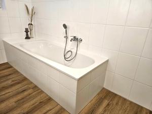 a bath tub with a shower in a bathroom at WieApart - Ruhig im Grünen, Parkplatz, zw. DUS/CGN in Leverkusen