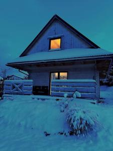 ein Haus mit einem Fenster und einem Zaun im Schnee in der Unterkunft Srokowa Hacjenda in Kreisau